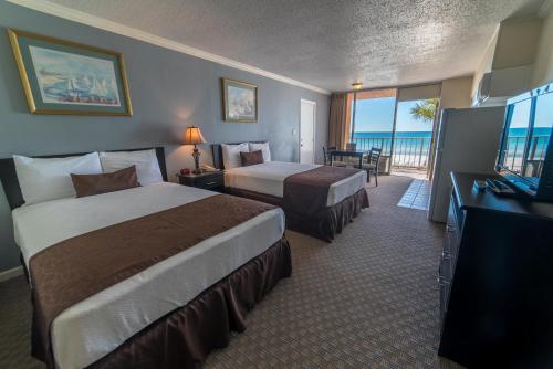 a hotel room with two beds and a flat screen tv at Seahaven Beach Hotel Panama City Beach in Panama City Beach