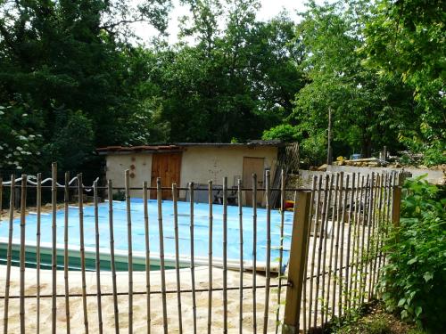 a fence with a swimming pool in front of a house at La Guelta in Saint-Alvère