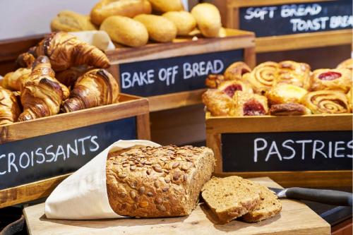 a loaf of bread sitting on a cutting board with pastries at Amrâth Grand Hotel Frans Hals in Haarlem