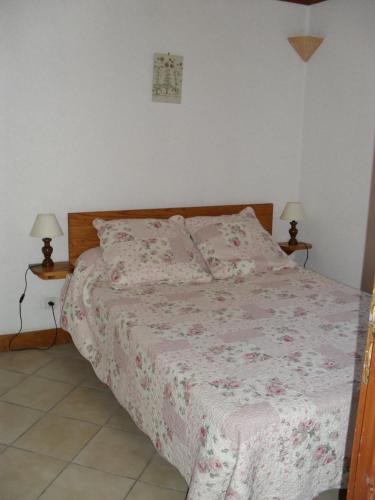 - une chambre avec un lit avec une couverture rose et 2 lampes dans l'établissement appartement vacances à la montagne RDC, à Génos