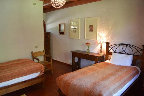 a bedroom with two beds and a desk and a chair at Hacienda Los Andes in Hurtado