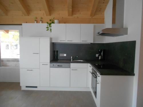 cocina con armarios blancos y encimera negra en Appartement Haus Petra, en Leogang