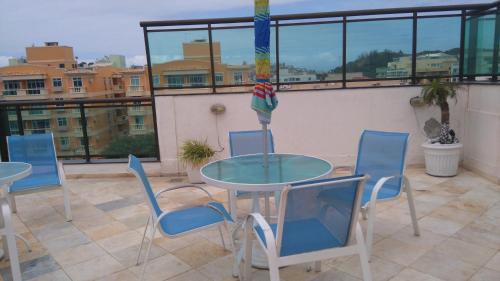 een patio met een glazen tafel en stoelen op een balkon bij Loft da Prainha Arraial do Cabo in Arraial do Cabo