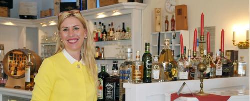 a woman standing behind a bar in a liquor store at Elbhotel Bleckede am Hafen in Bleckede