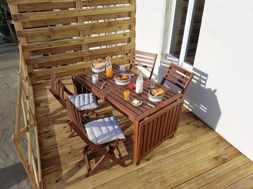 uma mesa de madeira com cadeiras e comida num deque em Les logis de la maisonnette em Mouchamps