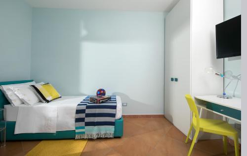 a bedroom with a bed and a yellow chair at Villa Claudia in SantʼAgata sui Due Golfi