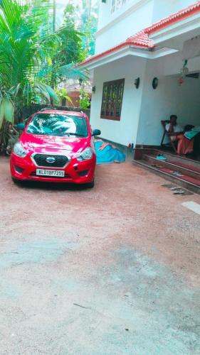 a red car parked in front of a house at Takashi Homestay North Paravur Near Muziris in North Paravur