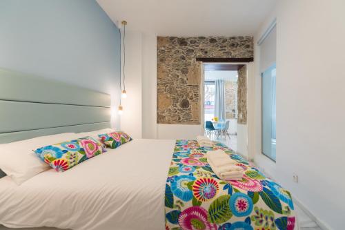 una camera da letto con un grande letto bianco con cuscini colorati di Cathedral Suites a Las Palmas de Gran Canaria