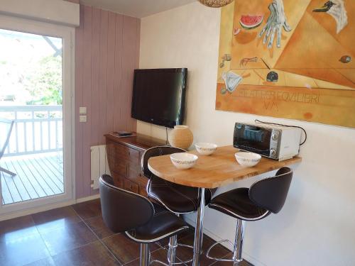 a kitchen with a table with chairs and a tv at Studio La Canonnière by Interhome in Le Piquey