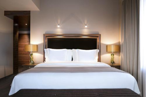 a bedroom with a large white bed with two lamps at Guarda Golf Hotel & Residences in Crans-Montana