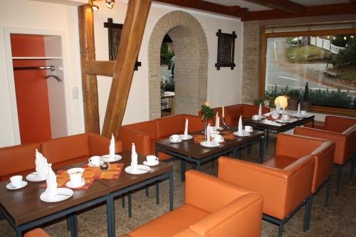 a dining room with tables and orange chairs at Pension Hotel Sartor in Kurort Altenberg