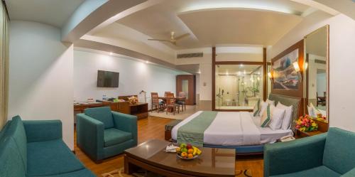 a hotel room with a bed and two blue chairs at Hotel Hindusthan International, Bhubaneswar in Bhubaneshwar