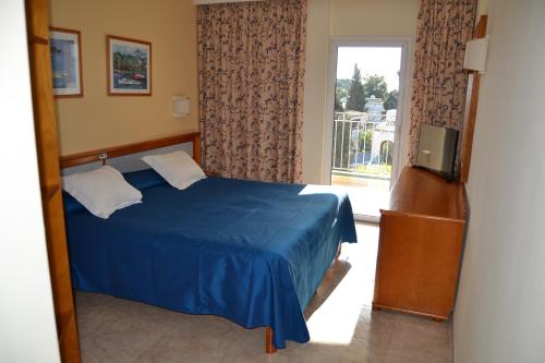Un dormitorio con una cama azul y una ventana en Hostal Leo d'Or, en Cala d´Or