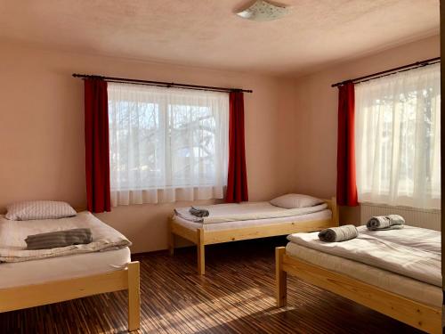 two beds in a room with red curtains at Kiss Kulcsosház in Bisericani