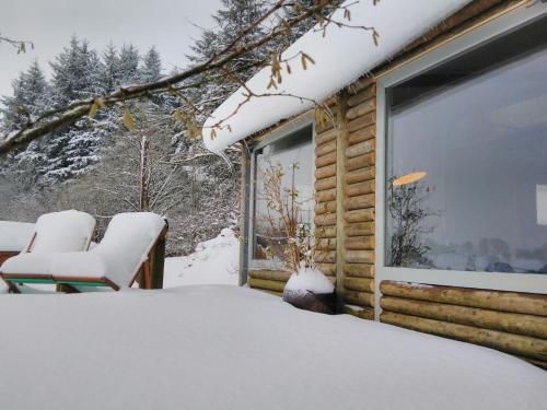a log cabin with snow on the porch at The Summerhouse in Llandegla