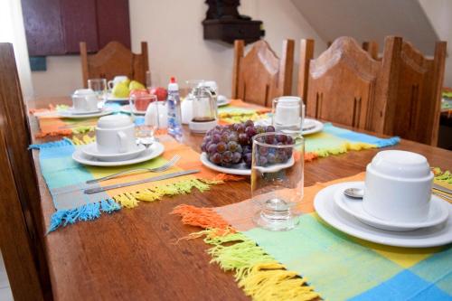 uma mesa de madeira com pratos e taças de fruta em Pousada do Getulio em Tiradentes