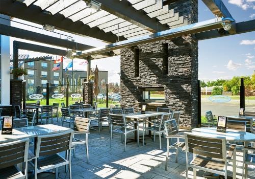 a patio with tables and chairs and a stone wall at Best Western Plus Edmonton Airport Hotel in Leduc