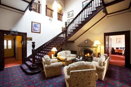 a living room with chairs and a staircase at Appleby Manor Hotel & Garden Spa in Appleby