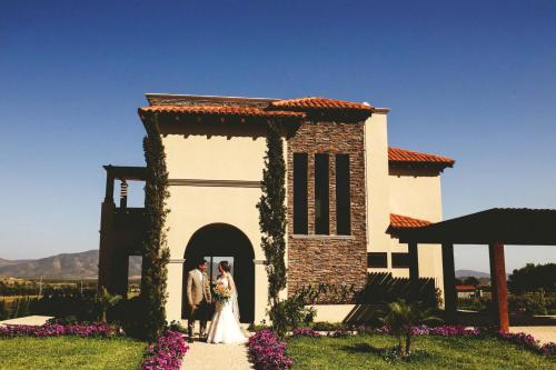 a bride and groom standing in front of a building at El Cielo Resort in Valle de Guadalupe