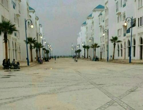 an empty street with palm trees and buildings at Résidence al massirra in Fnidek