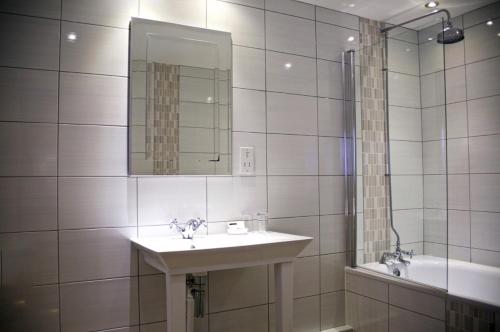 uma casa de banho com um lavatório, um espelho e uma banheira em The Golden Lion Hotel em Northallerton