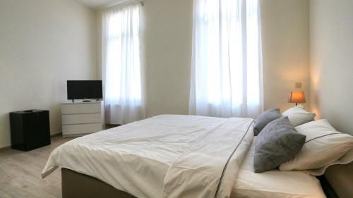 1 dormitorio con 1 cama blanca grande y TV en B&B Handelshof, en Lier