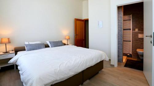 um quarto com uma grande cama branca e uma casa de banho em B&B Handelshof em Lier