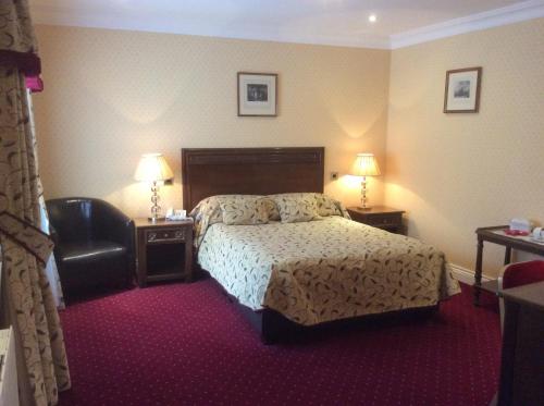 a hotel room with a bed and a chair at The Golden Lion Hotel in Northallerton