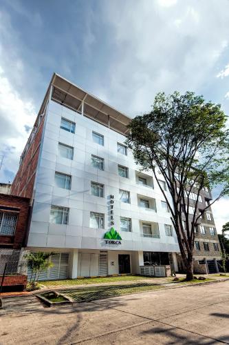 a large white building with a tree in front of it at Torca Hotel in Cali