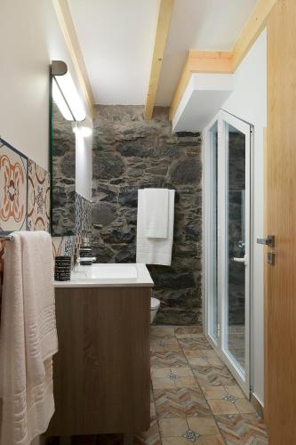a bathroom with a sink and a stone wall at Casa do Leme in Arco da Calheta