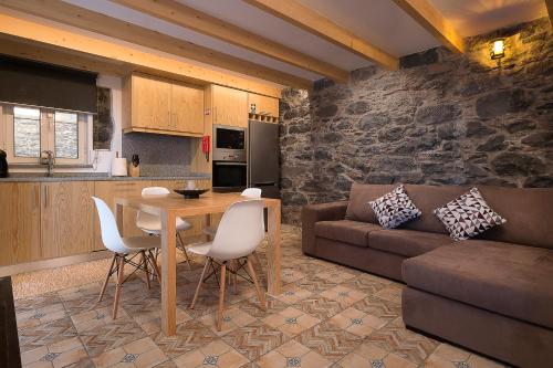 eine Küche und ein Wohnzimmer mit einem Tisch und einem Sofa in der Unterkunft Casa do Leme in Arco da Calheta