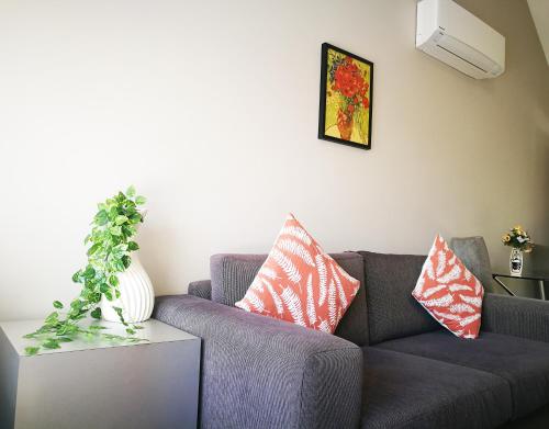 a living room with a gray couch with pillows on it at Belmont Motor Inn in Christchurch