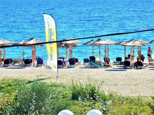 a group of people sitting on a beach with umbrellas at Mezonetes Toroni in Toroni