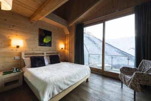 a bedroom with a bed and a large window at Chalet Morel 1586 Hotel & Spa in Limone Piemonte