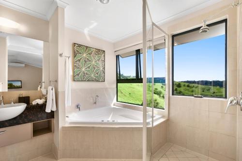 a bathroom with a tub and a sink and a window at Top Of The Hill in Maleny