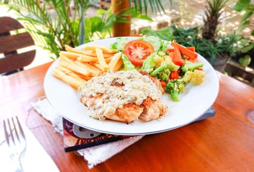 a plate of food with vegetables and meat and fries at Naturela in Uluwatu