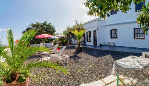 a patio with chairs and umbrellas in front of a house at Bodega Goyo in Puntallana