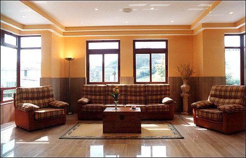 a living room with couches and a table and windows at Hotel Piedra in Perlora