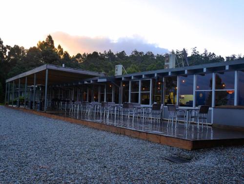 a building with tables and chairs in front of it at Pedder Wilderness Lodge in Strathgordon