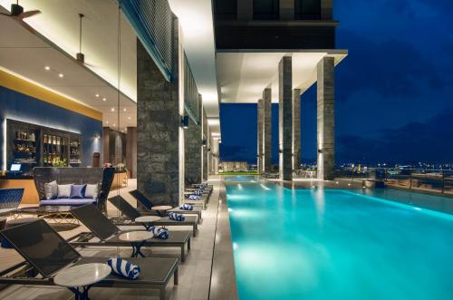 a hotel swimming pool with lounge chairs and a city at Brighton Grand Hotel Pattaya - SHA Extra Plus in North Pattaya