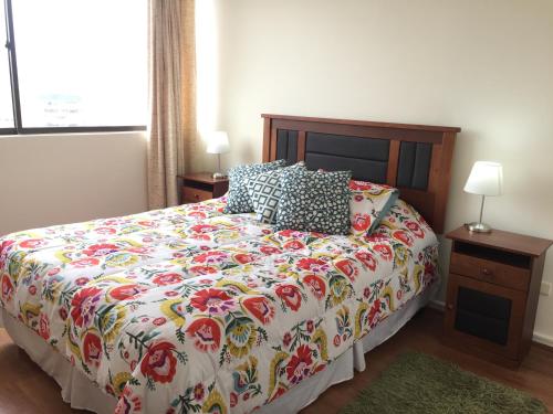 a bedroom with a bed with a floral comforter at Departamento 8 Norte, Torre del Mar in Viña del Mar