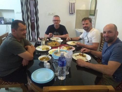 a group of men sitting around a table eating food at El Casa Homestay in Cochin