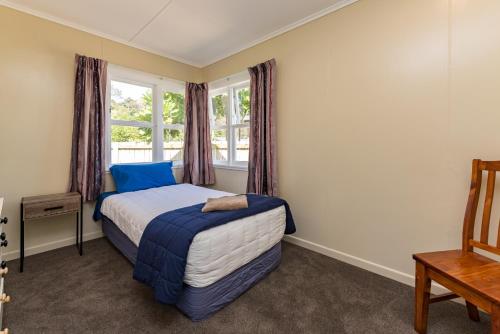 a bedroom with a bed and a window at Waitangi Beach Bach 30A in Paihia