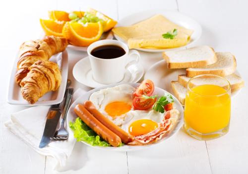 un plato de desayuno con huevos y pan y una taza de café en Mini Hotel Voyage, en Novokuznetsk