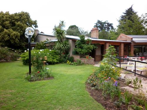 une maison avec une cour fleurie et une lumière de rue dans l'établissement Hosteria Pastoral & Spa, à La Cumbre