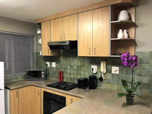 Una cocina con gabinetes de madera y un horno de estufa. en Sand & Sea Self-Catering Apartments, en Swakopmund