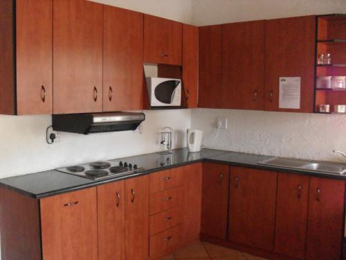 a kitchen with wooden cabinets and a black counter top at Anna Boeremeisie Guesthouse in Benoni