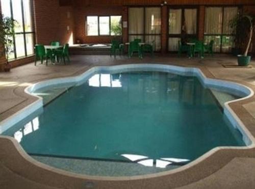 a large swimming pool in a building with tables and chairs at Elsinor Motor Lodge in Wollongong