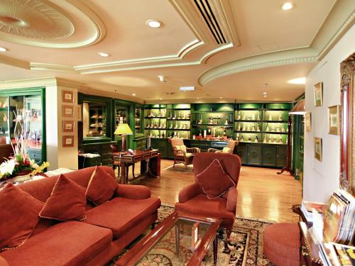 a living room with a couch and chairs in a library at Merdeka Palace Hotel & Suites in Kuching