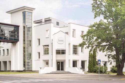 a white building with a tree in front of it at Estonia Resort Hotel & Spa in Pärnu
